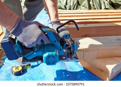 Blue Collar Carpenter Using Electric Saw For Wood Cutting On Site