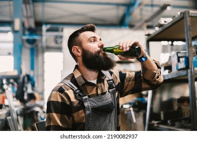 A Blue Collar Worker Drinking Beer In Factory On A Break.