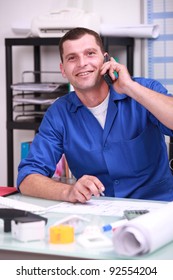 Blue Collar Worker In His Office And On The Phone