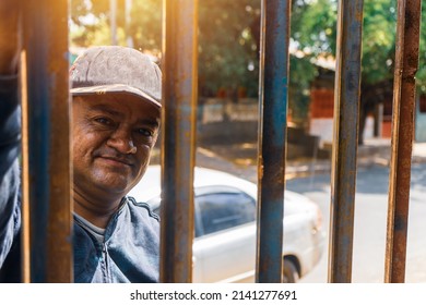 Blue Collar Worker From Latin America Looking Through A Fence