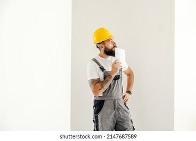 A Blue Collar Worker Standing In Painted Room And Planning Next Step.