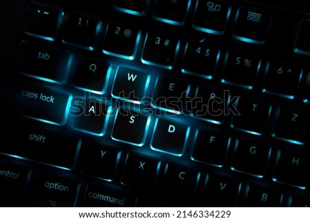 Blue color backlighted computer keyboard. Close-up of highlighted default keys in games associated with movements. Professional computer game playing, e-sport business and online world concept.