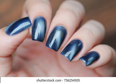 Blue Color Cat's Eye Manicure With A Nail Polish Bottle In Hand