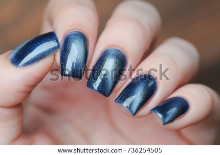 blue color cat's eye manicure with a nail polish bottle in hand