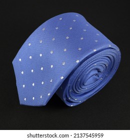 Blue Color Neck Tie Rolled White Dotted With Black Background 