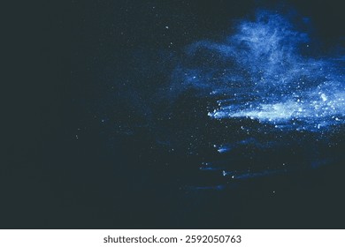 Blue color powder explosion cloud on black background. Closeup of Blue dust particles splash.