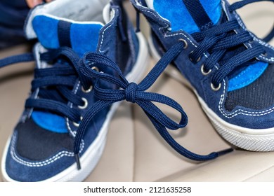 Blue Color Shoes For Kids With Tied Laces, In A Modern Car. Shoes On The Steering Wheel, On The Car's Seat Or In A Boy's Hands. April Fools Day Prank.