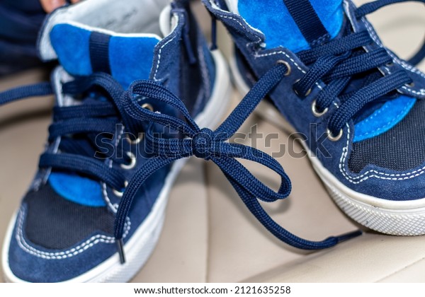 blue color shoes for kids with tied laces, in\
a modern car. Shoes on the steering wheel, on the car\'s seat or in\
a boy\'s hands. April Fools Day\
prank.