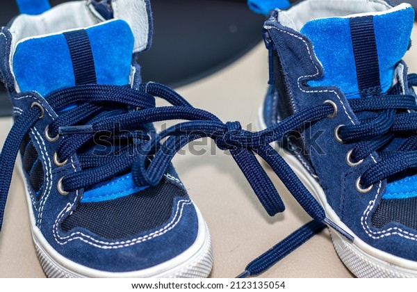 blue color shoes for kids with tied laces, in\
a modern car. Shoes on the steering wheel, on the car\'s seat or in\
a boy\'s hands. April Fools Day\
prank.