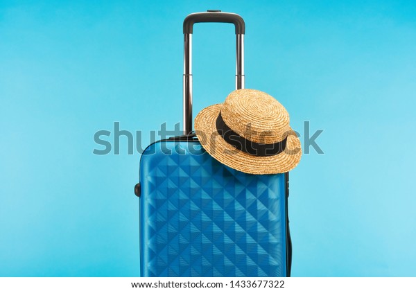 blue colorful travel bag with handle and straw hat\
isolated on blue 