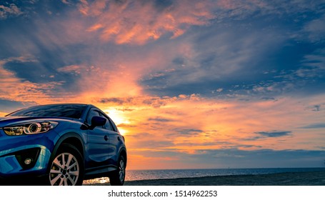 Blue Compact SUV Car With Sport And Modern Design Parked By Beach At Sunset. Hybrid And Electric Car Technology. Car Parking Space. Automotive Industry. Car Care Business Background. Beautiful Sky.