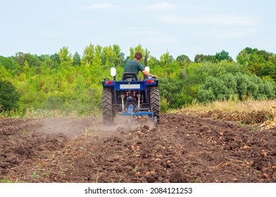 A blue compact tractor is harvesting potatoes in the field. Farm equipment at - Shutterstock ID 2084121253