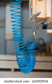 Blue Compressed Pneumatic Air Hose With Pistol Hanging At Screw