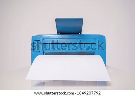 Blue computer printer with a sheet of paper extending forward