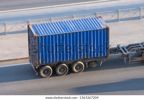 Blue\
container trailer driving on a highway at high\
speed