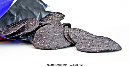 Blue Corn Tortilla Chips Spilling From A Bag On White Background. Horizontal.