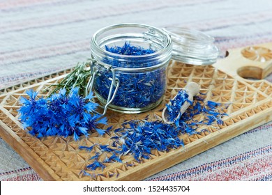 Blue cornflower or centaurea flower tea is good as diuretic, in cosmetics and eyewash, fresh blossom and a jar with dry petals nearby, closeup, copy space, herbal drinks concept
