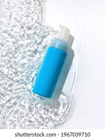 Blue Cosmetic Bottle On The Water Surface. Blank Label For Branding Mock-up. Flat Lay, Top View.