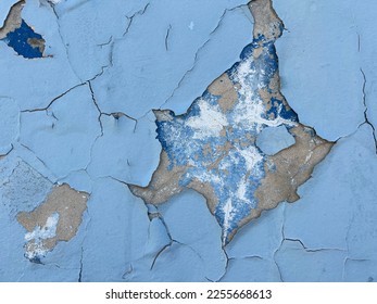 Blue cracked peeling flaking paint on exposed old urban concrete wall