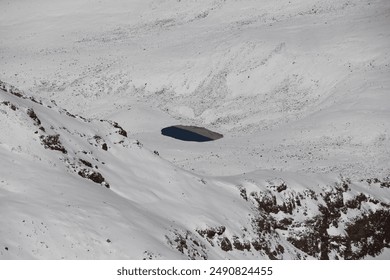 Blue crater lake in snowy mountains, Aerial view in winter. Snow-capped peaks and clear water. - Powered by Shutterstock