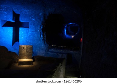 Blue Cross With Recliners To The Bottom With Salt Formations In Its Structure In The Cathedral Of Salt In Colombia.