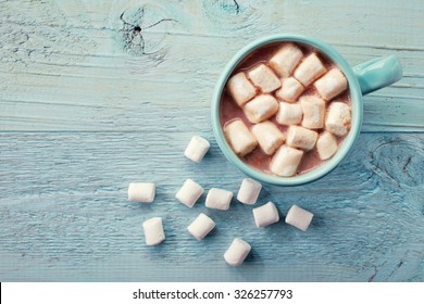 Blue Cup Of Hot Cocoa With Marshmallows On Blue Wooden Background