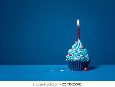 Pastel azul con rociadores rojos y velas encendidas en un fondo azul.