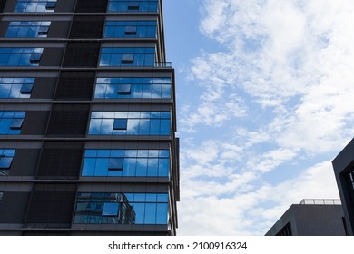 Blue Curtain Wall Made Of Toned Glass And Steel Constructions Under Cloudy Sky