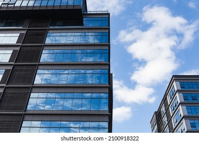 Blue Curtain Wall Made Of Toned Glass And Steel Constructions Under Cloudy Sky