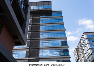 Blue Curtain Wall Made Of Toned Glass And Steel Constructions Under Cloudy Sky