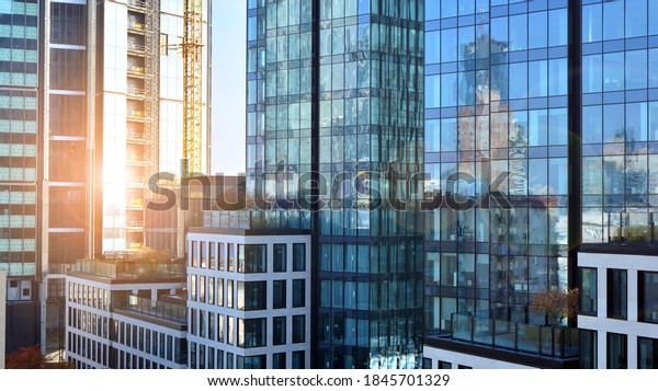 Blue curtain wall made of\
toned glass and steel constructions under blue sky. A fragment of a\
building. Glass facades on a bright sunny day with sunbeams in the\
blue sky.