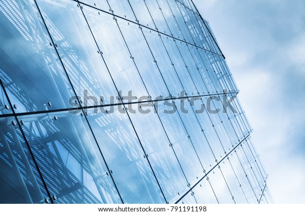 Blue curtain wall made of toned glass and\
steel constructions under cloudy\
sky