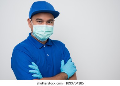 Blue delivery asian man wearing protection mask and medical rubber gloves standing with arm crossed on isolated white background safety deliver concept. - Powered by Shutterstock