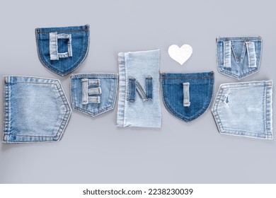 Blue denim cut off shreds on a gray background. A set of different jeans pockets. The word denim from pieces of jeans fabric. Textiles and clothing sustainability. top view. 