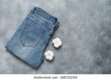 Blue denim jeans with cotton flowers on rustic gray background. Top view, flat lay. The concept of natural eco fabrics. Textured object, selective focus. - Powered by Shutterstock