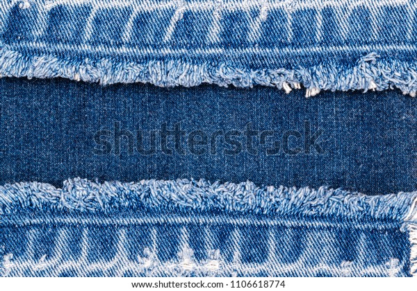 Blue denim jeans fabric frame.\
Bleached denim fabric with fringe edge on blue denim background,\
text place, copy space. Worn Jeans Casual Double Color\
patch
