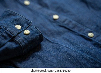 Blue denim shirt cuff with white buttons close-up. Garment background