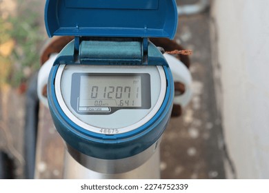 Blue digital water meter. Closeup of old and dirty electronic tap water flow meter outdoor with digital display and selective focus.