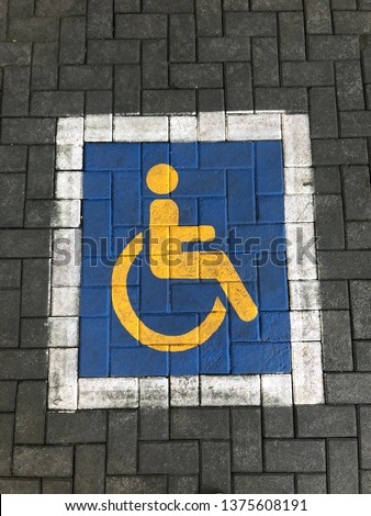 Blue disable people sign above con block in parking area.