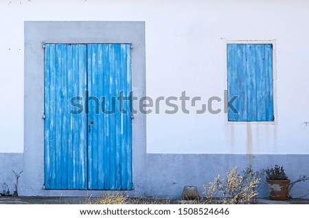 Blue door with a window closed in a mediterranean house with white wall