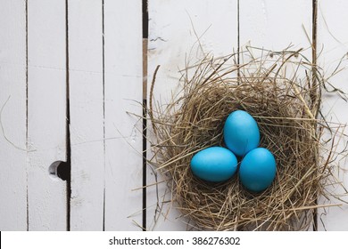 Blue Easter eggs in nest on wooden background