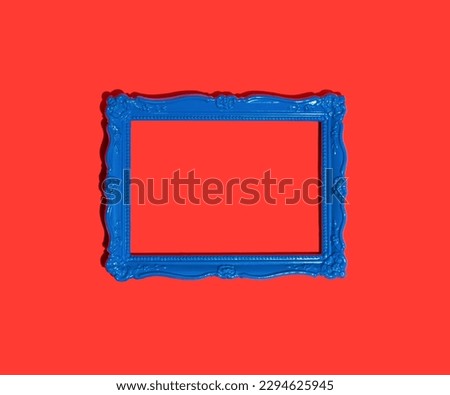 Blue empty frame isolated on red background. Decorative detail, retro inspired background. Creative pop art concept of antique frame. Comparison of vintage and contemporary style.