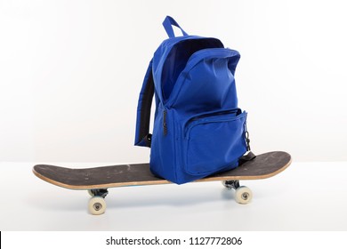 Blue Empty Open Backpack On Top Of Skateboard