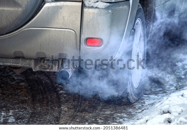 Blue exhaust smoke. Car engine smoking.\
Smoking exhaust pipe, closeup. Car with gasoline or diesel engine.\
Engine warming up at idle in winter\
season