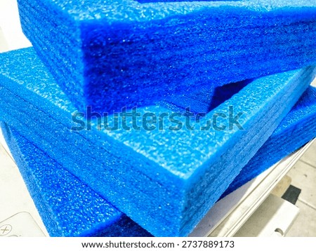 blue expanded polyethylene (EPE) foam packaging trays stacked on a tiled floor, designed for protective cushioning and industrial shipping solutions.