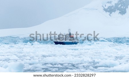 Blue expeditionary ship in the ice of the Antarctic. Mountains in the background of the Antarctic Peninsula. High quality photo