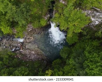 Blue Eye Theth Lake Waterfall in Theth (Thethi) National Park in north of Albania, beautiful place with cold blue water and green forest around, aerial footage on the drone from above
