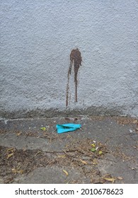 Blue Face Mask Laying On A Ground With Dried Blood Spot On Wall. Pneumonia Is Heavy Covid Coronavirus Aftermath Consequences