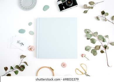 Blue Family Or Wedding Photo Album  With Blank Space For Text, Eucalyptus Leaf, Retro Camera And Dry Rose Buds On White Background. Flat Lay, Top View.