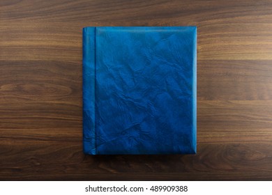 Blue Faux Leather Photo Album Or Year Book Cover, Blank, Placed On A Dark Colored Wooden Table. 